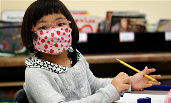 girl smiles while wearing mask